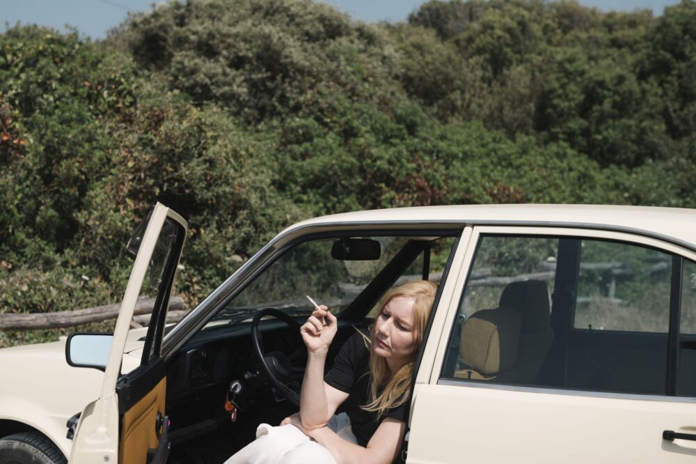Nachdenklich sitzt Ingeborg Bachmann (Sandra Hüller) in ihrem Auto auf einem Parkplatz am Meer.